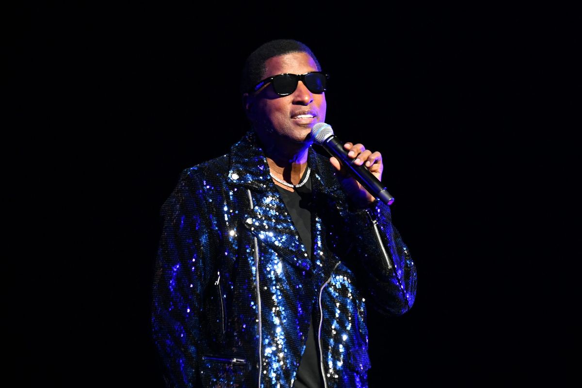 Babyface wearing Black sunglasses with a shiny blue bedazzled jacket and microphone in hand