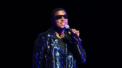 Babyface wearing Black sunglasses with a shiny blue bedazzled jacket and microphone in hand