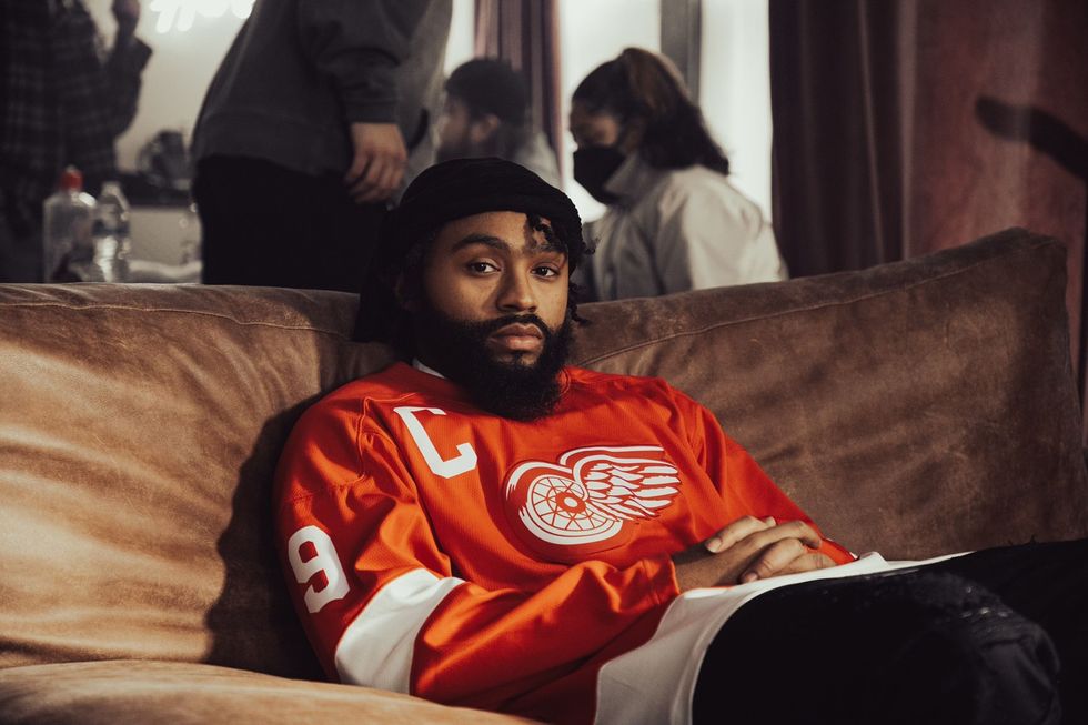 Courtney Bell lays back on a couch wearing a Detroit Redwings jersey. 