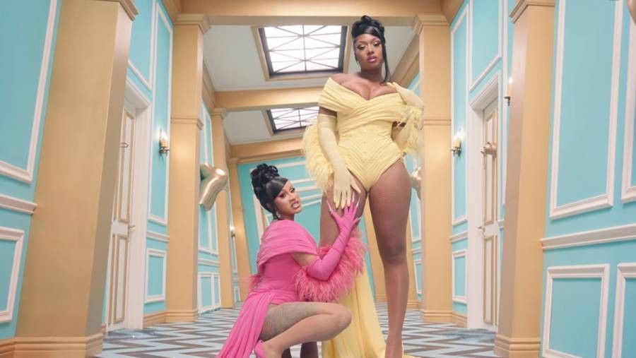 Female rappers Cardi B wearing pink, posing with Megan Thee Stallion wearing yellow