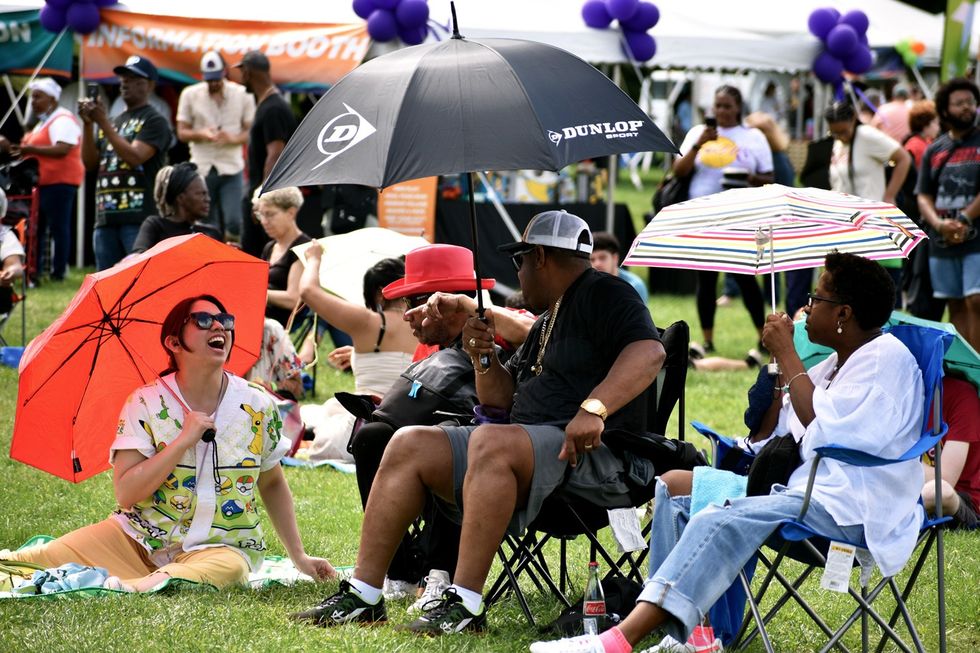 Festival goers laugh in the shade of umbrellas brought to ward off the forecasted storms at BAMFest in Franklin Park, June 24, 2023.