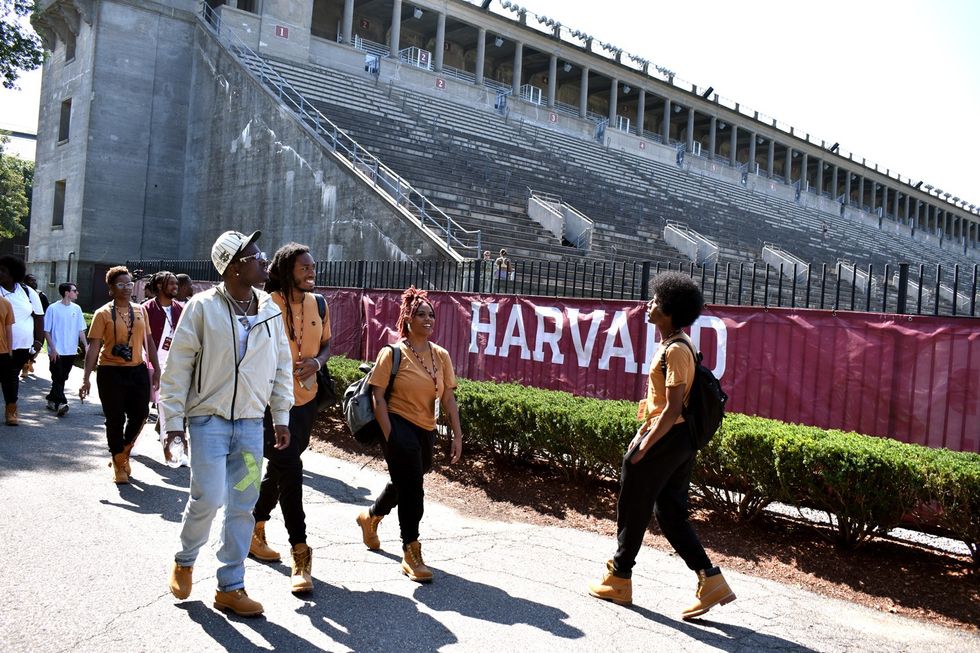 IDK (left) walks past the Harvard Athletic Complex while leading the 2023 No Label Academy class on a tour of campus.