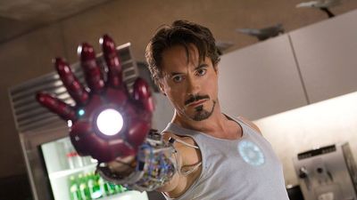 Tony Stark holds the Iron Man hand up to the camera.