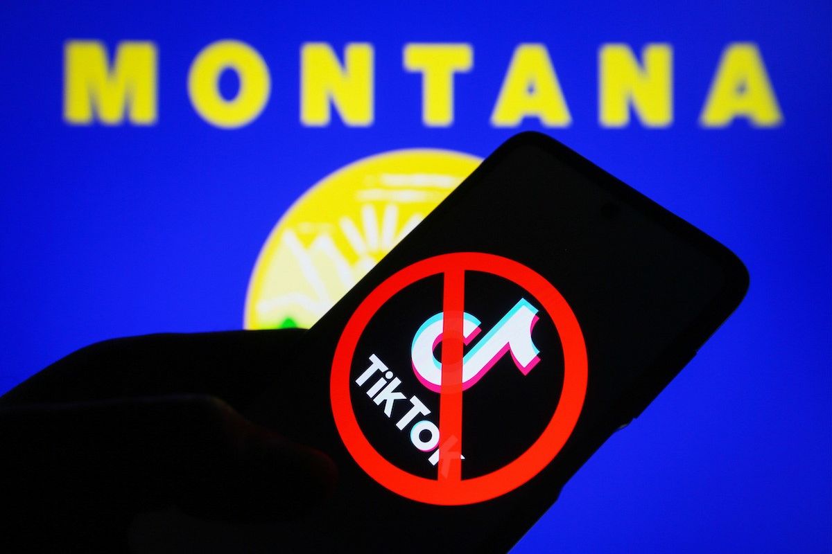 In this photo illustration, a crossed-out TikTok logo is seen on a smartphone and flag of the state of Montana on a pc screen.