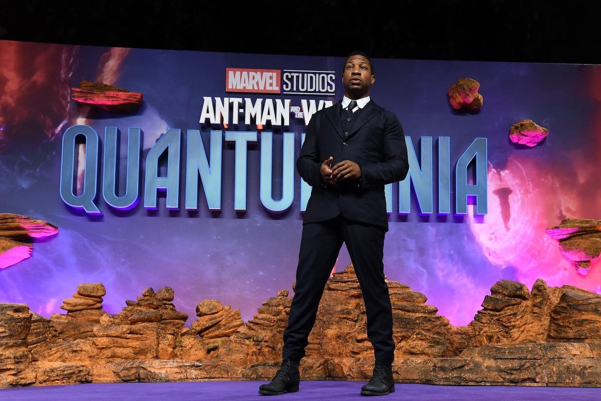 Jonathan Majors standing in front of Quantumania sign