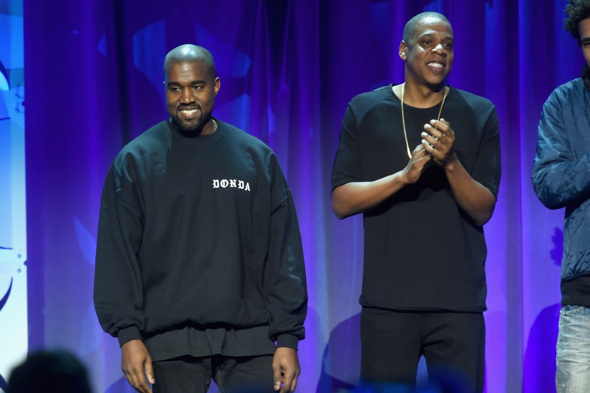 Kanye West and JAY-Z wearing all black, standing next to each other at the 2015 TIDAL launch event