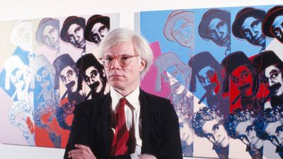 American Pop Artist Andy Warhol, half-length Portrait in front of Marx Brothers Screen-print from his series Ten Portraits of Jews of the Twentieth Century, Jewish Museum, New York City, New York, USA, Bernard Gotfryd, 1980.