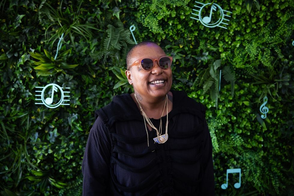 Meshell Ndegeocello wearing glasses, smiling with chains on her neck.