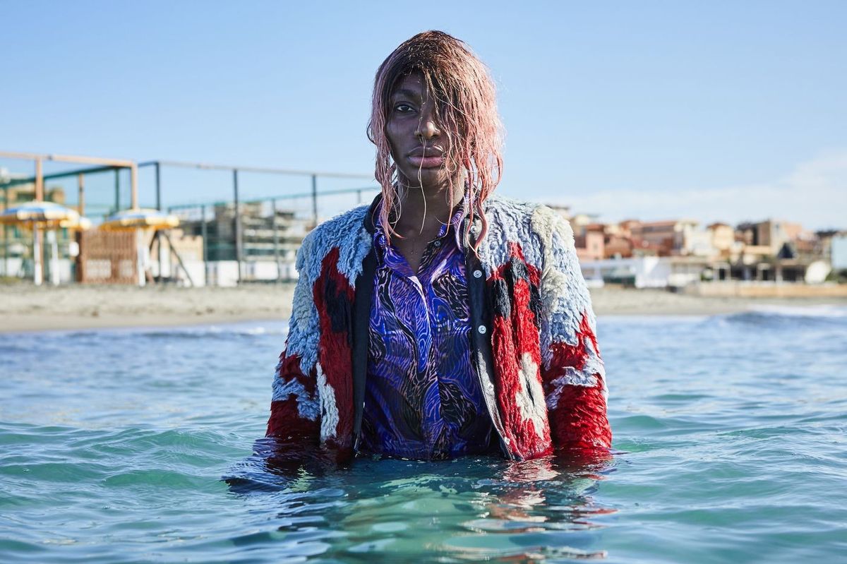 Michaela Coel in water with colorful jacket.