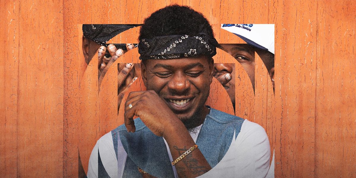 Mick Jenkins smiling with chain on his arm.