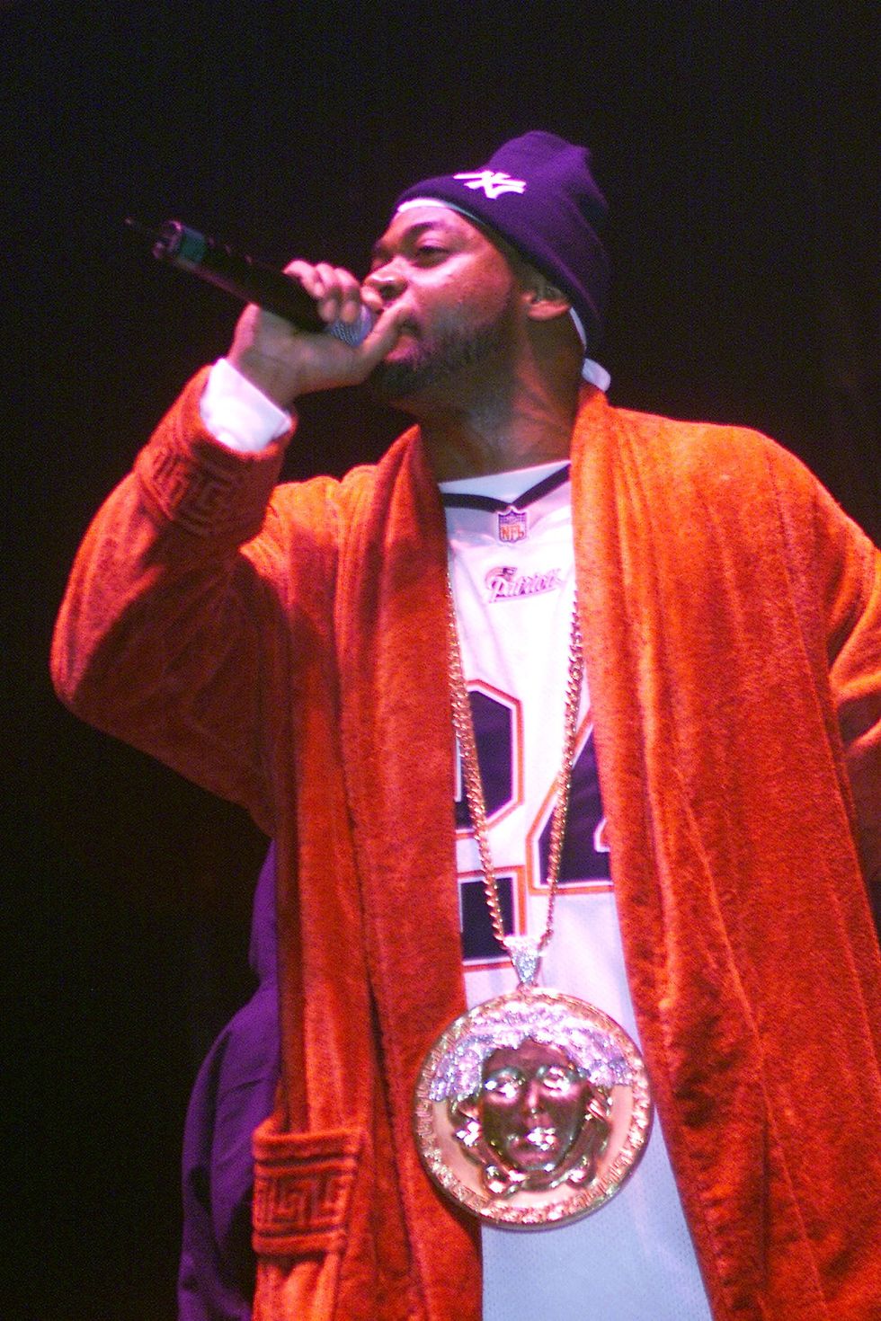 Rapper Ghostface Killah wearing orange robe and big chain holding mic best rap verses