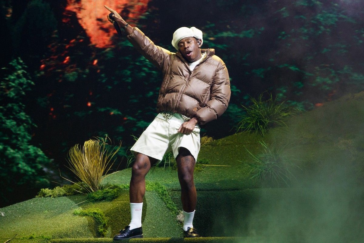 tyler, the creator performing with hat and brown coat