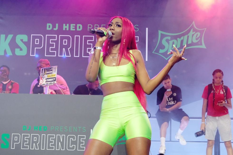 female rapper with red hair in lime green bike shorts