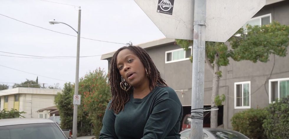 female rapper leans on car in California street