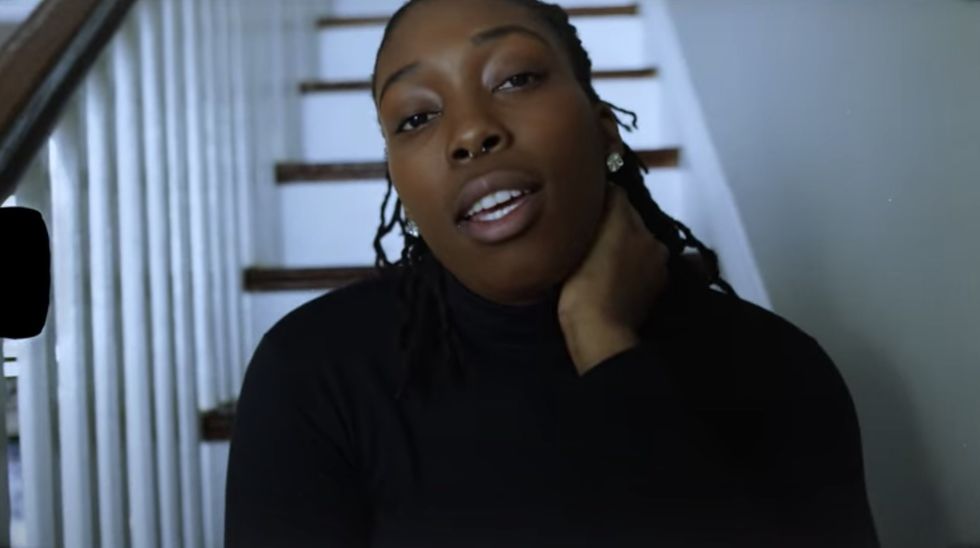 female rapper in black turtleneck sitting on the stairs