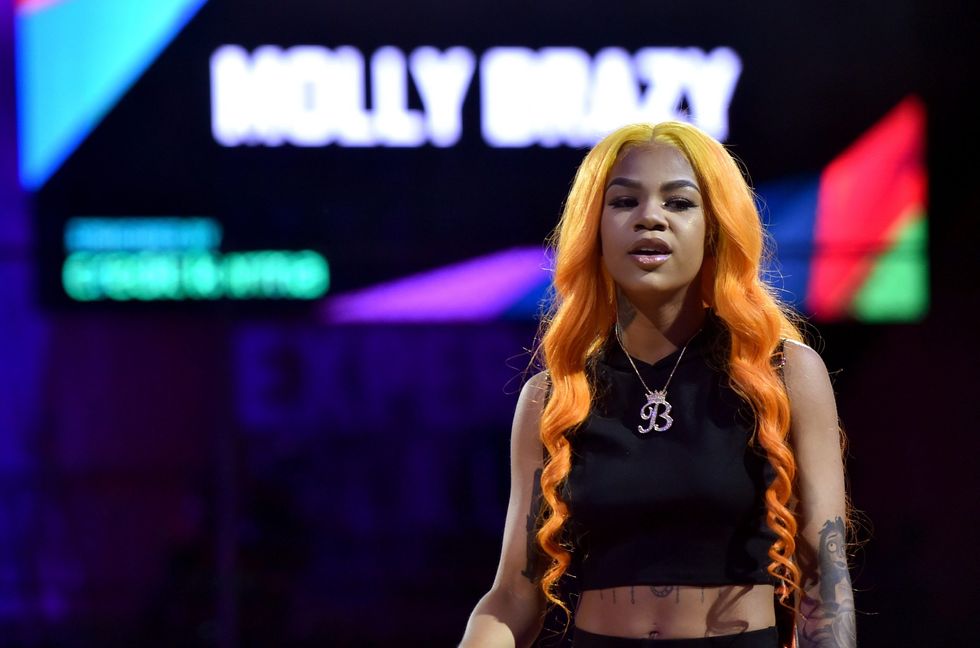 Molly Brazy female rapper with orange hair and chain onstage