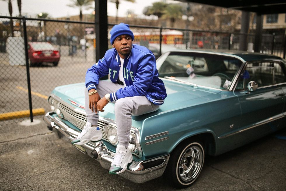 Rapper Curren$y on top of car