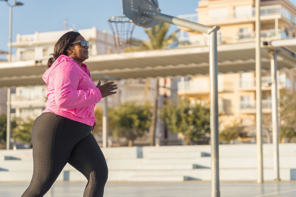African American female athlete in sportswear and sneakers jogging on city street, one of many self care tips