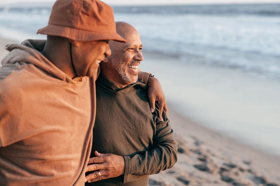 Two men embrace on the beach, another example of good self care tips